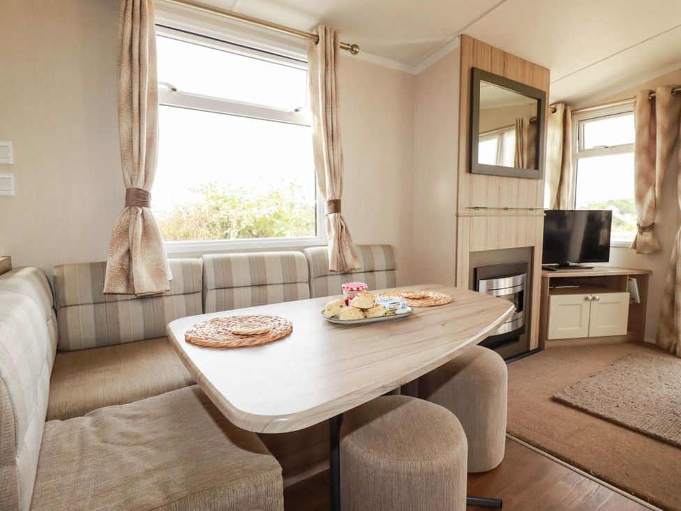 A dining room with a table and television at Roslenn in St Agnes