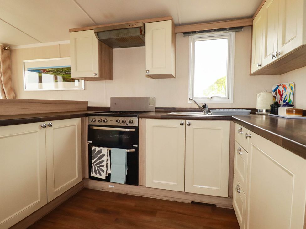 A kitchen with cabinets, oven, sink and window at Roslenn St Agnes