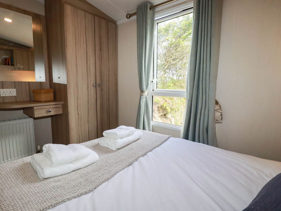 A bedroom with a bed and towels on the side at Roslenn in St Agnes