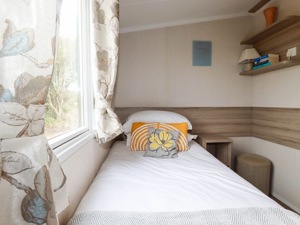 A bedroom with a bed and shelf at Roslenn in St Agnes