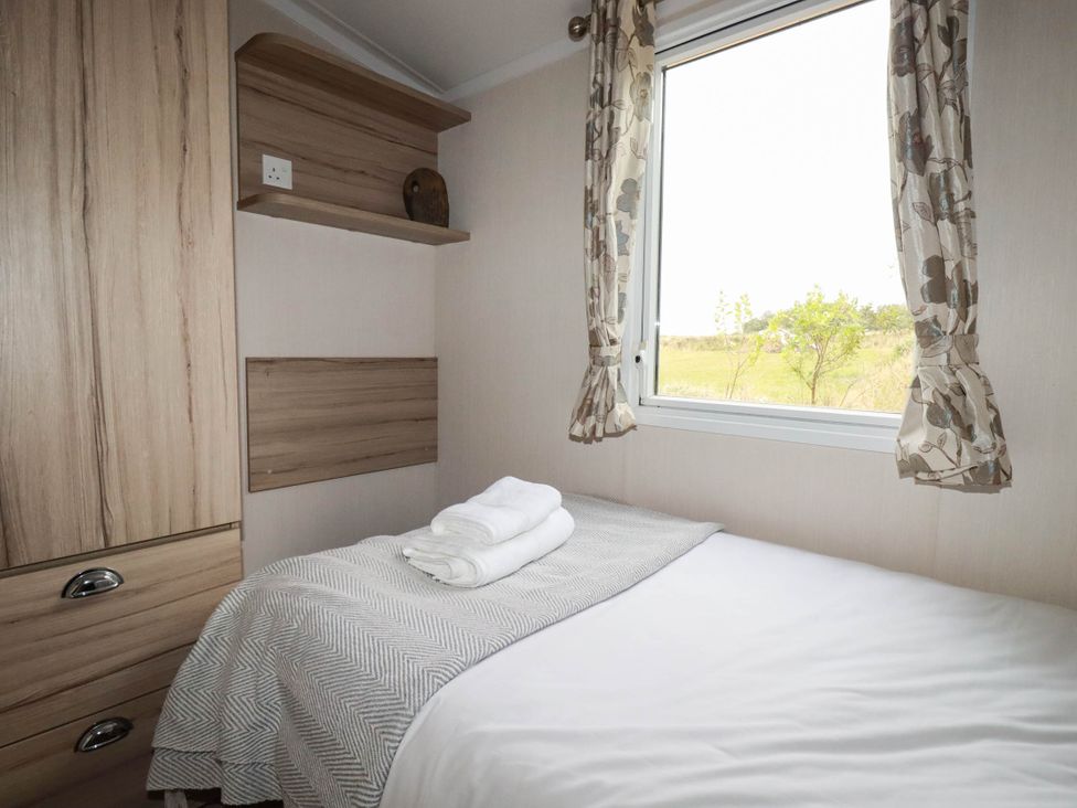 A bedroom with a bed and window at Roslenn in St Agnes