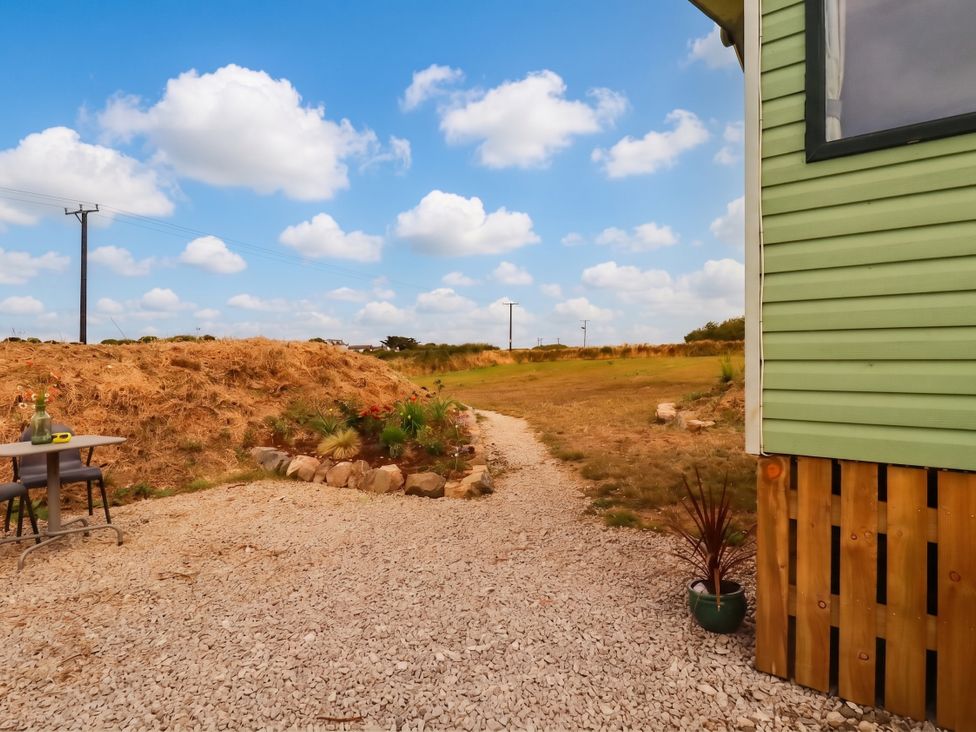 A path leading to a garden with a table and chairs at Roslenn in St Agnes