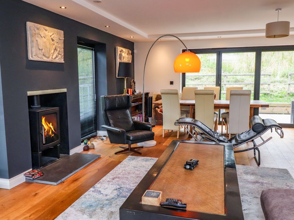 A living room with a fireplace and dining table at The Barn at Bryn Eithin, Colwyn Bay
