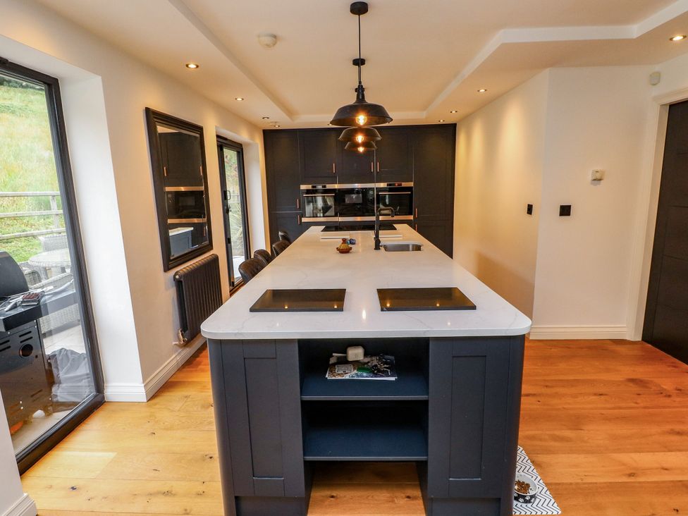 A kitchen with a central island and modern appliances at The Barn at Bryn Eithin, Colwyn Bay