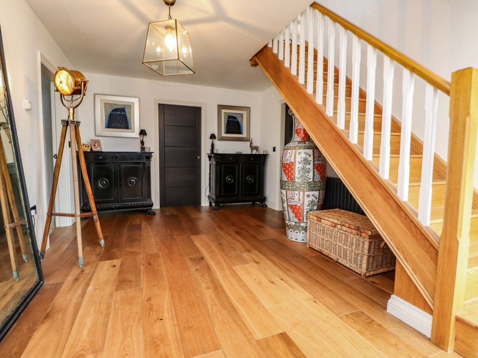 A hallway with a staircase and cabinets at The Barn at Bryn Eithin in Colwyn Bay