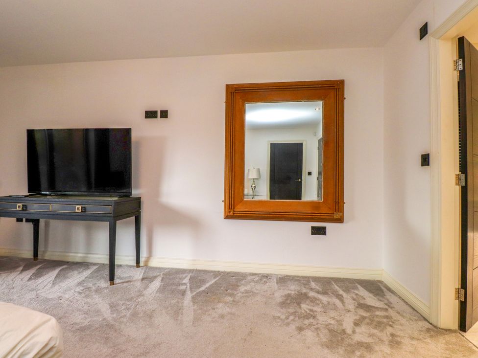 A bedroom with a television and a mirror at The Barn at Bryn Eithin in Colwyn Bay
