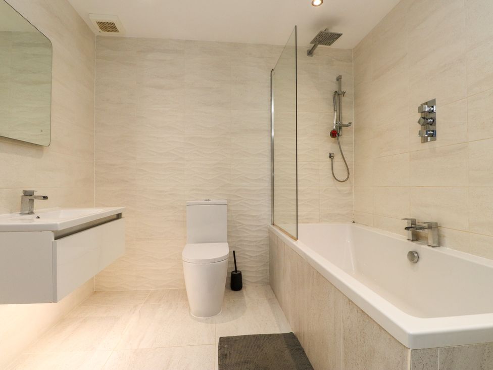 A bathroom with a tub, toilet and sink at The Barn at Bryn Eithin in Colwyn Bay