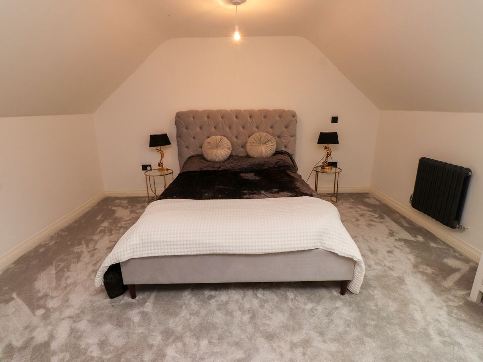 A bedroom with a bed and bedside tables at The Barn at Bryn Eithin in Colwyn Bay