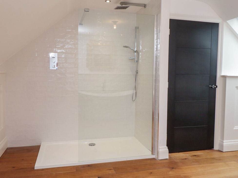 A bathroom with a shower and a door at The Barn at Bryn Eithin in Colwyn Bay
