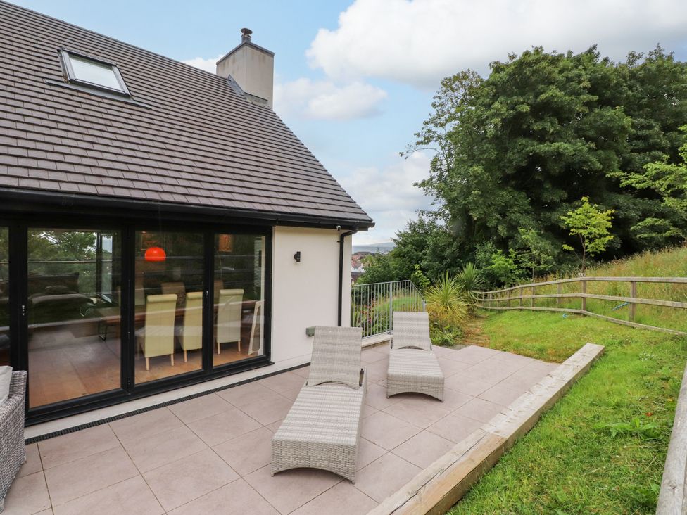 An outdoor area with patio chairs and trees at The Barn at Bryn Eithin Colwyn Bay