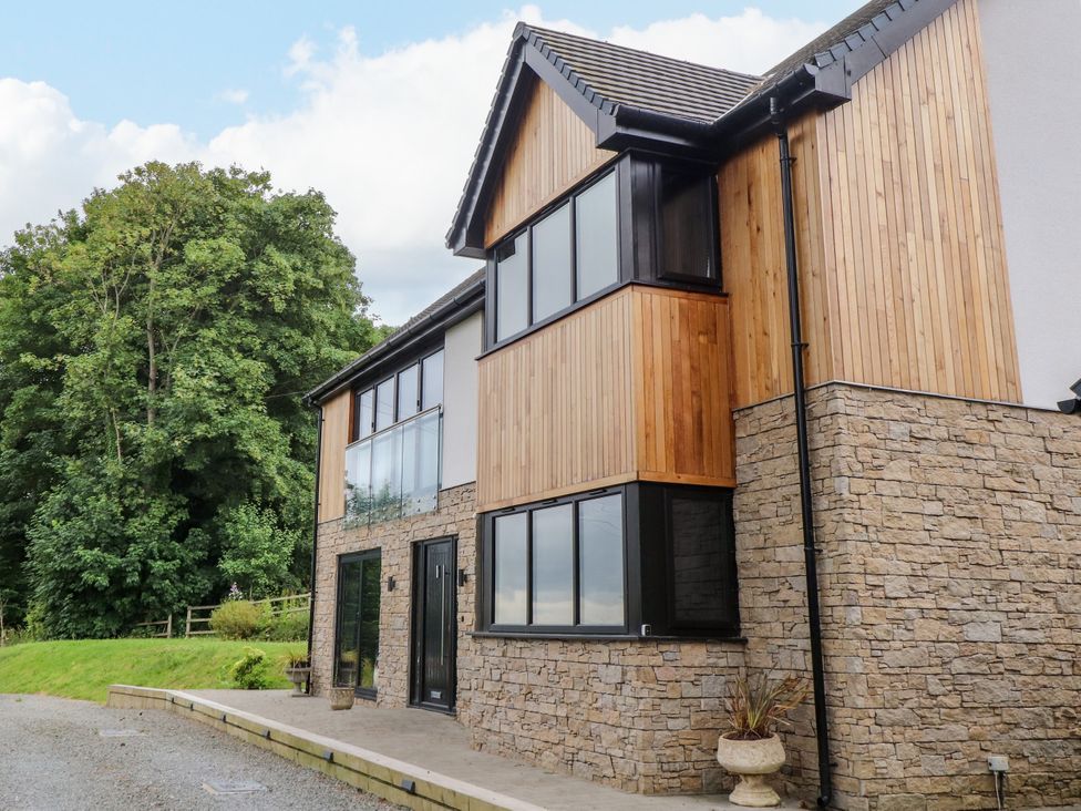 An exterior view of a house with stone and wood features at The Barn at Bryn Eithin in Colwyn Bay