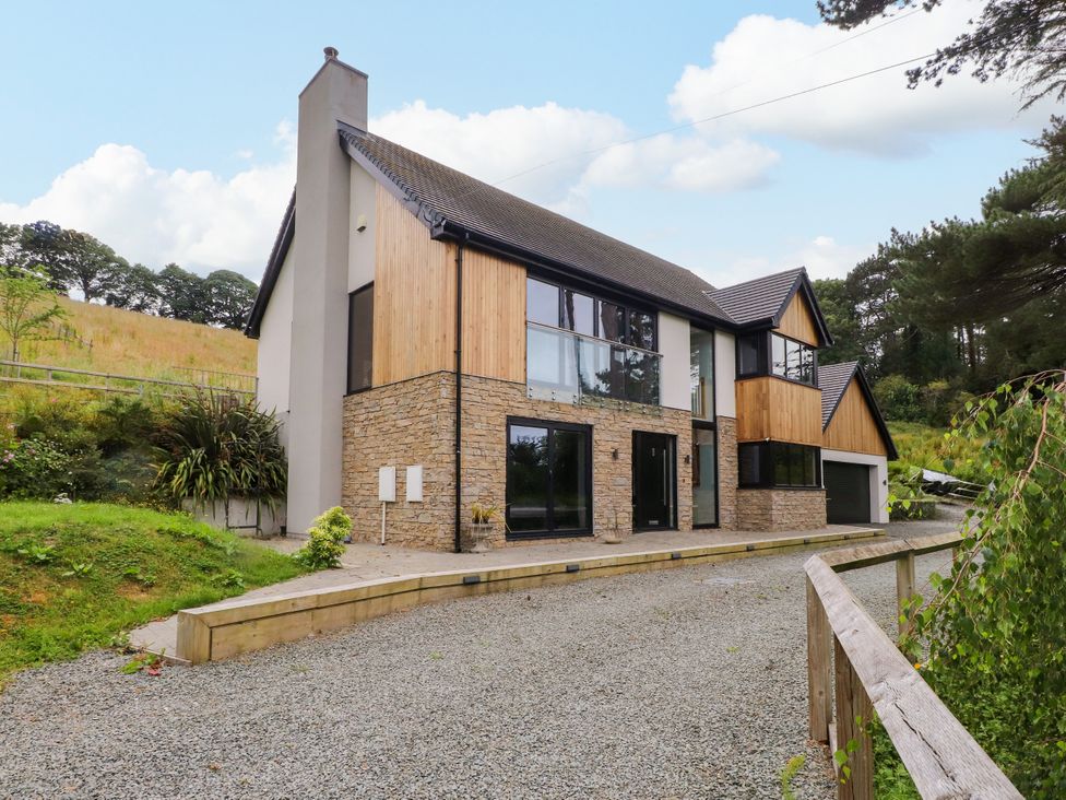 A house with a stone and wood exterior and a garage at The Barn at Bryn Eithin in Colwyn Bay