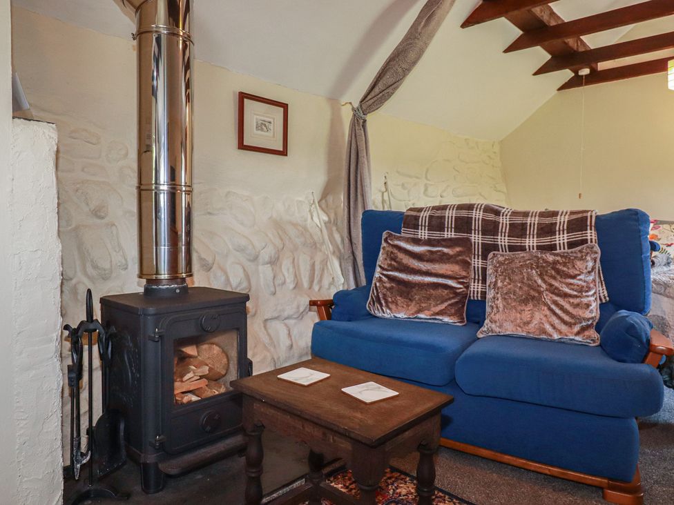 A living room with a blue armchair and a wood stove at Moorland Retreat in Bodmin