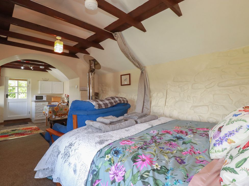 A living room with a couch and kitchenette at Moorland Retreat in Bodmin
