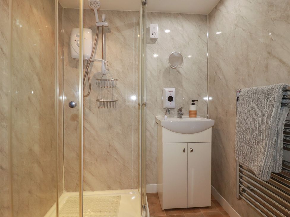 A bathroom with a shower, sink, towel rail, and soap dispenser at Moorland Retreat in Bodmin