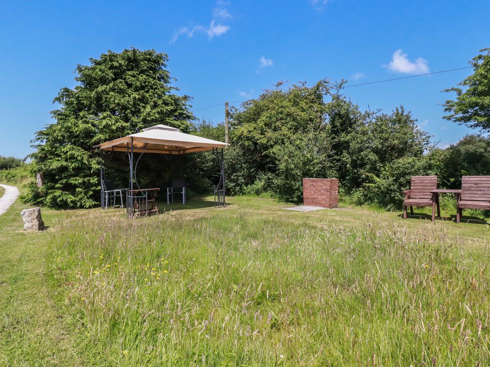 A garden with a table and chairs under a canopy at Moorland Retreat in Bodmin