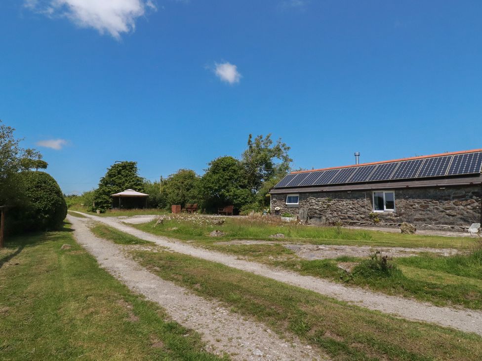 An outdoor view featuring a stone building with solar panels and a gazebo at Moorland Retreat in Bodmin