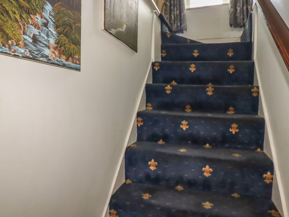A staircase with carpet and paintings at Rose Cottage in Launceston