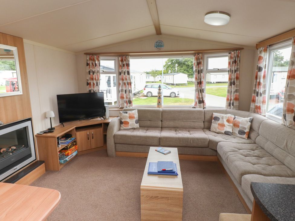 A living room with a sofa and television at 10 Cambrian Park Pwllheli