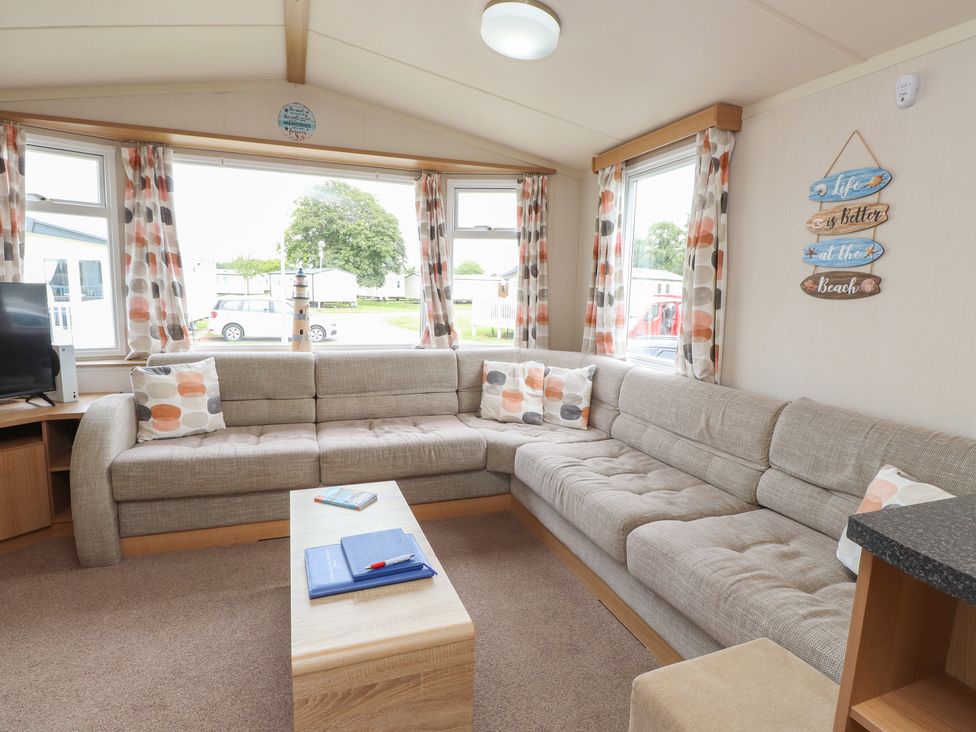 A living room with a sofa and coffee table at 10 Cambrian Park in Pwllheli