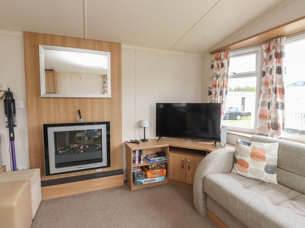 A living room with a sofa and a tv at 10 Cambrian Park Pwllheli