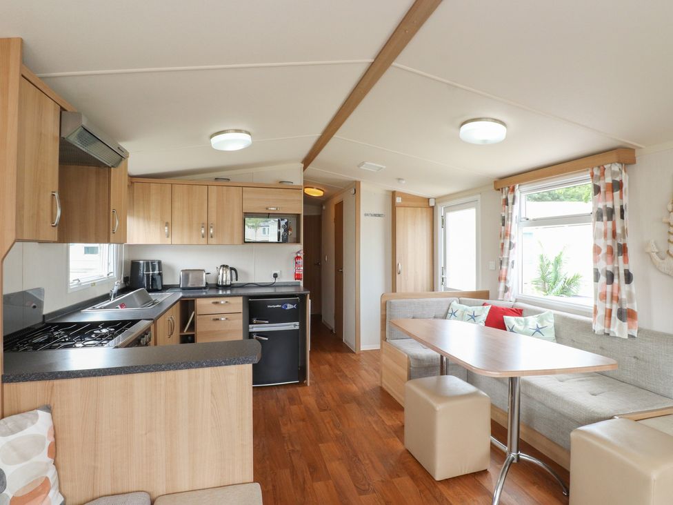 A kitchen with table and seating area at 10 Cambrian Park Pwllheli
