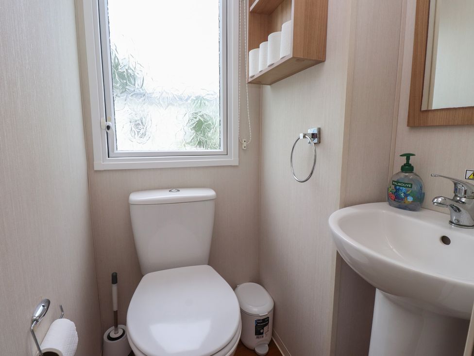 A bathroom with a toilet and hand basin at 10 Cambrian Park Pwllheli