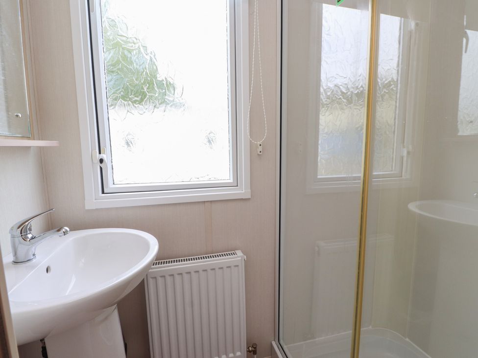 A bathroom with a sink and a shower at 10 Cambrian Park Pwllheli