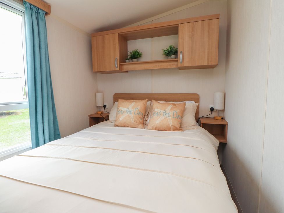 A bedroom with a bed and bedside tables at 10 Cambrian Park in Pwllheli