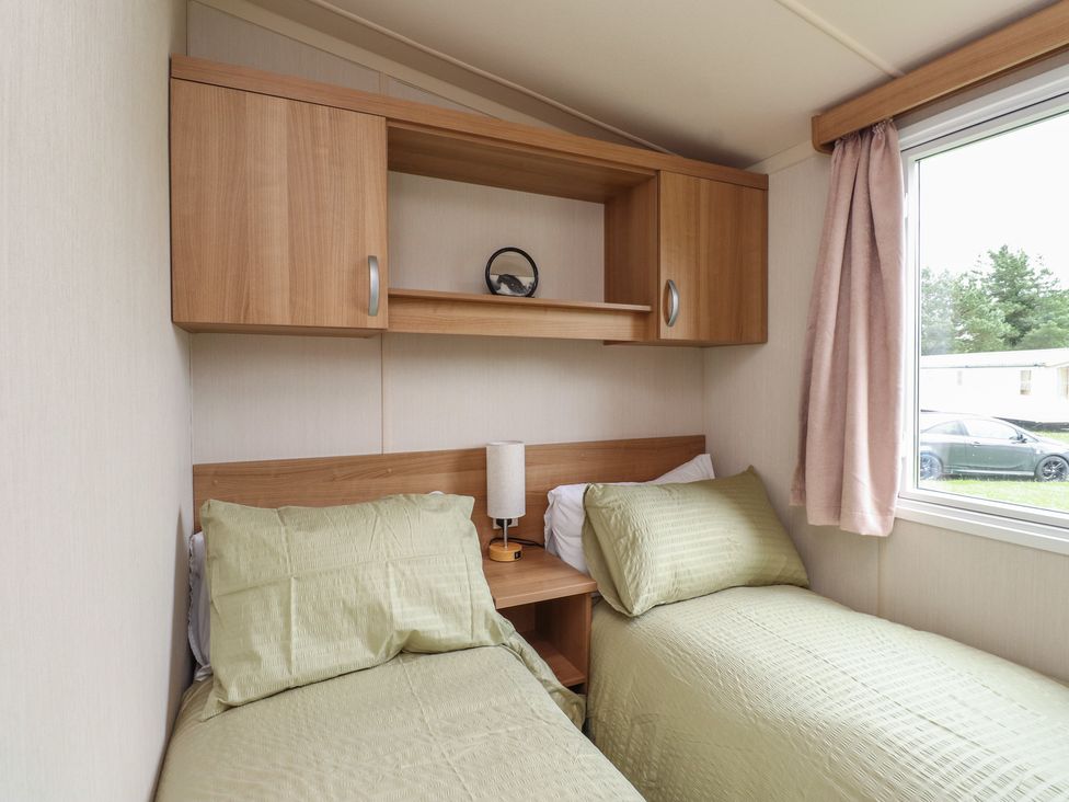 A bedroom with two single beds and a shelf at 10 Cambrian Park Pwllheli
