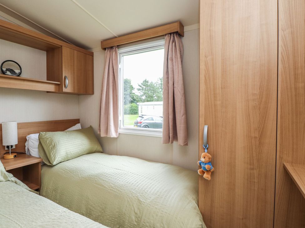 A bedroom with twin beds and a window at 10 Cambrian Park Pwllheli
