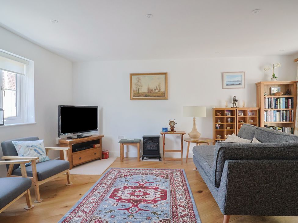 A living room with a sofa and television at L'Ancresse Cottage in Lyme Regis
