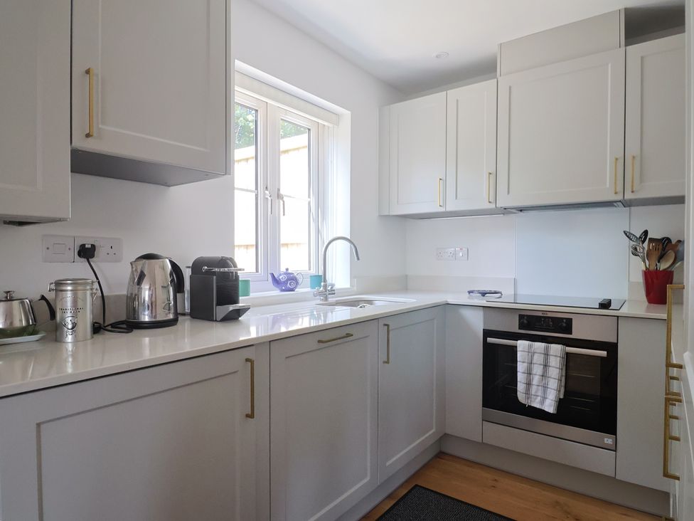 A kitchen with cabinets and appliances at L'Ancresse Cottage in Lyme Regis