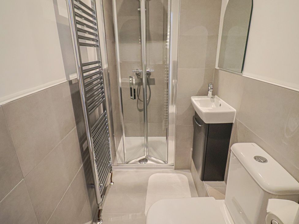 A bathroom with a shower, sink, and toilet at L'Ancresse Cottage in Lyme Regis