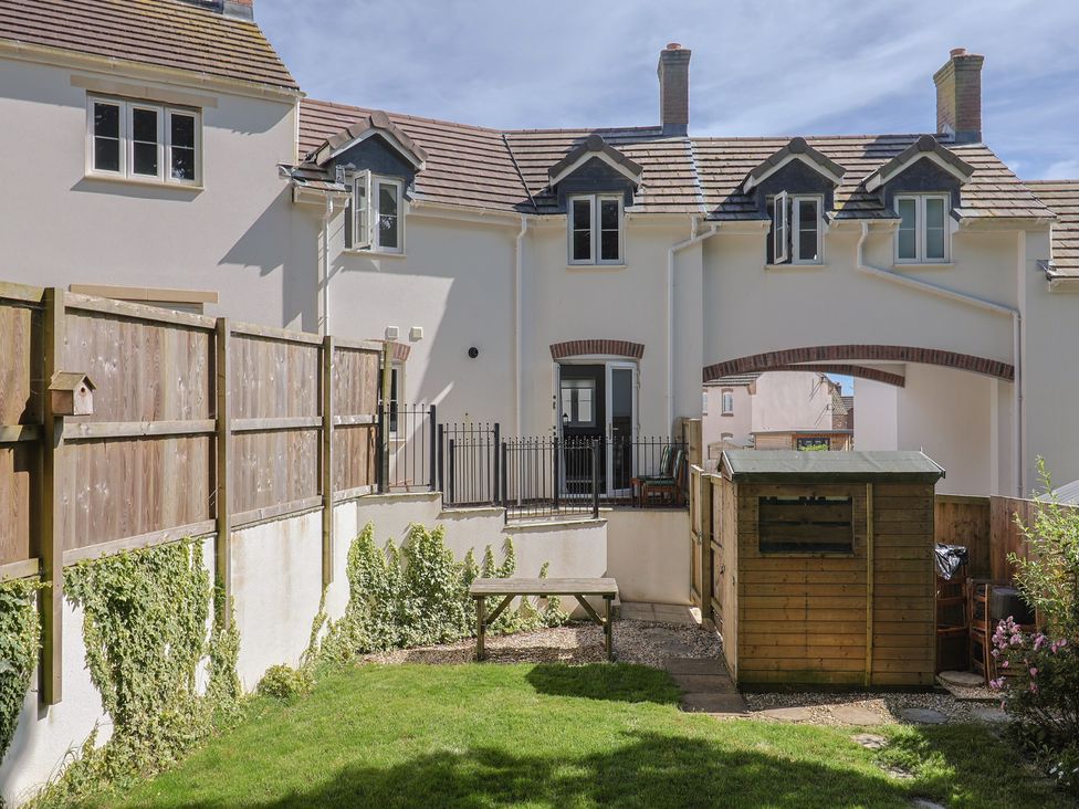 A garden with a shed and table at L'Ancresse Cottage in Lyme Regis