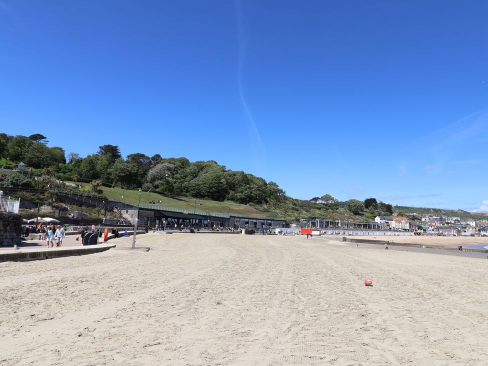 A beach with people and buildings in the background at L'Ancresse Cottage in Lyme Regis