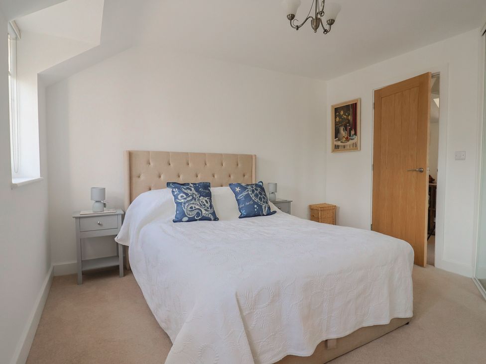 A bedroom with a bed and bedside table at L'Ancresse Cottage in Lyme Regis