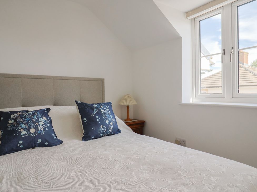 A bedroom with a bed and lamp at L'Ancresse Cottage in Lyme Regis