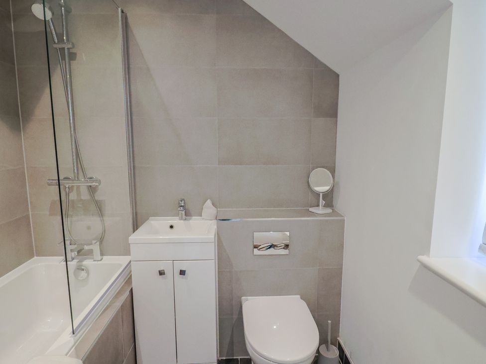 A bathroom with a bathtub and sink at L'Ancresse Cottage in Lyme Regis