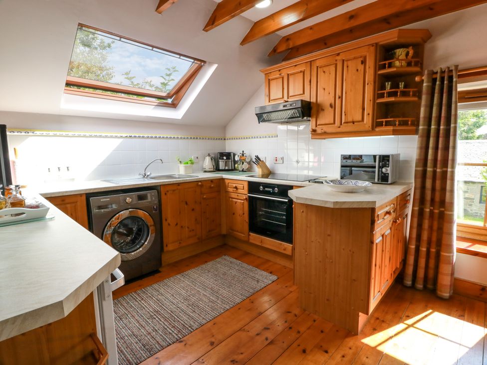A kitchen with appliances and wooden cabinets at Buchanan’s Bothy Glencarse