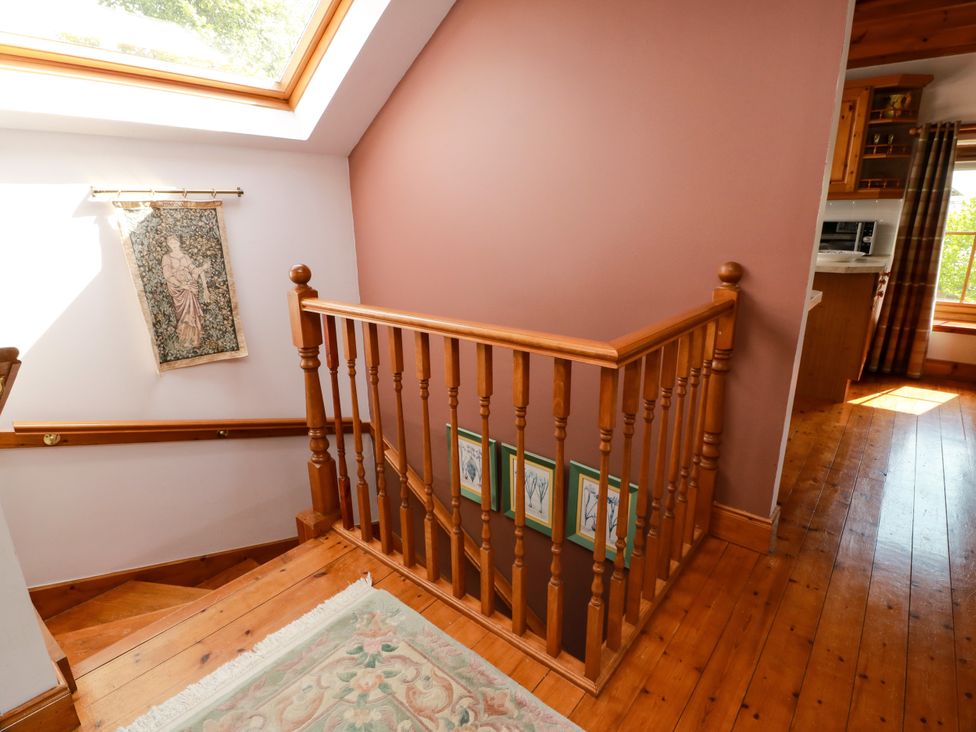 A staircase with wooden railing and artwork at Buchanan’s Bothy in Glencarse