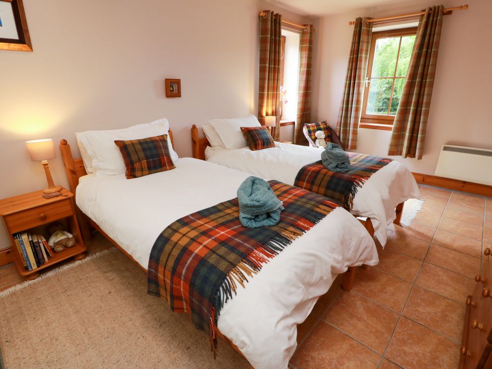 A bedroom with two beds and a nightstand at Buchanan’s Bothy Glencarse