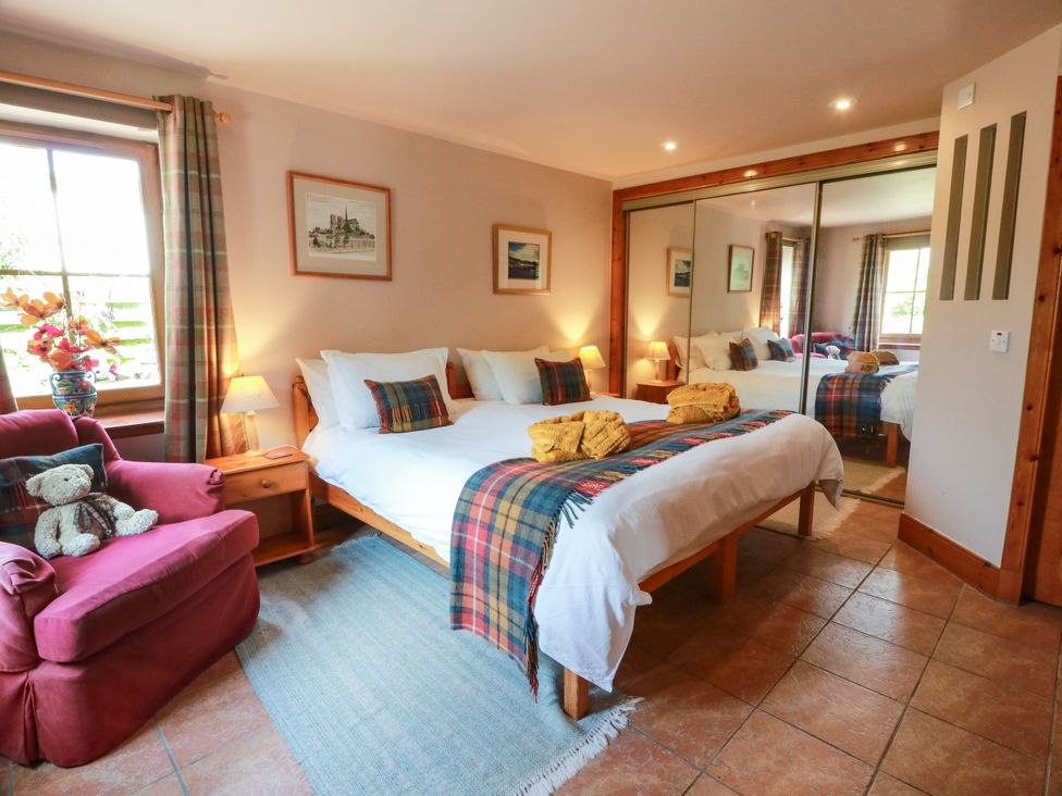 A bedroom with a bed and sofa at Buchanan’s Bothy in Glencarse