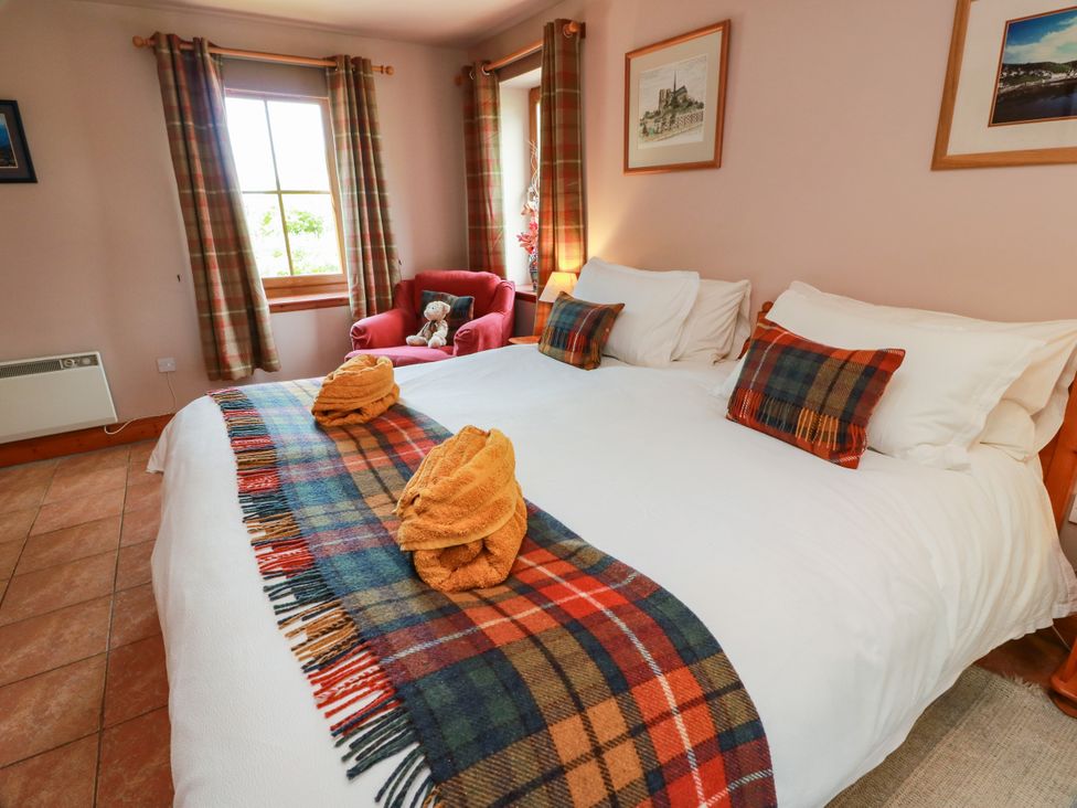 A bedroom with a bed, chair, and window at Buchanan’s Bothy in Glencarse