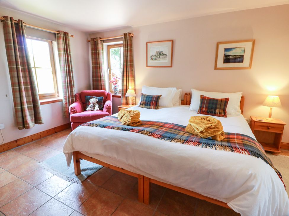A bedroom with a bed and a chair at Buchanan’s Bothy in Glencarse
