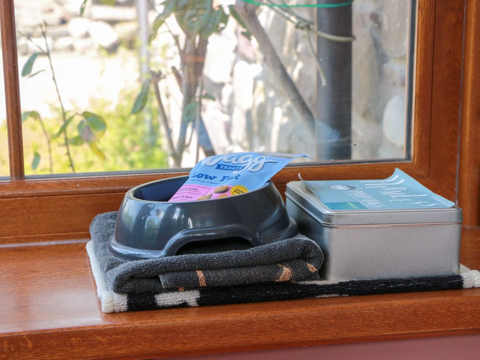 A pet food bowl with treats and a storage tin on a kitchen windowsill at Buchanan’s Bothy in Glencarse