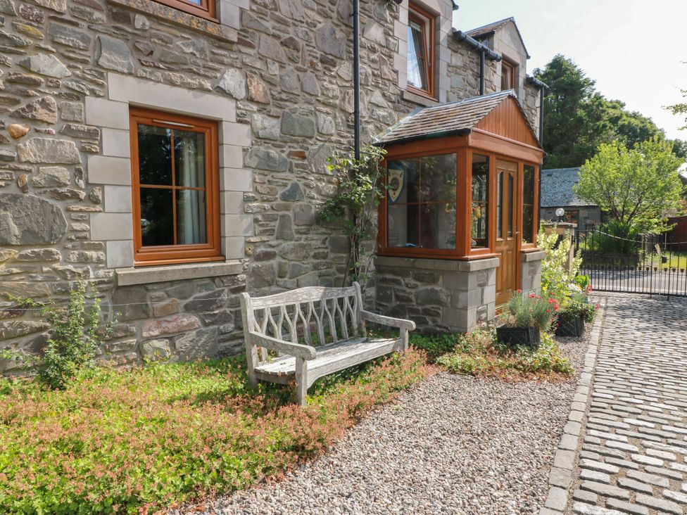 A garden with a stone wall and a bench at Buchanan’s Bothy in Glencarse