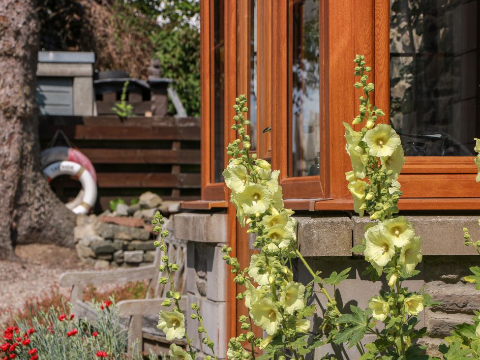 A garden with flowers and wooden window at Buchanan’s Bothy in Glencarse