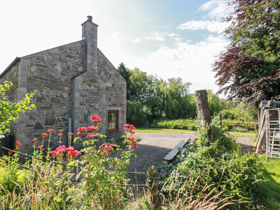 A stone building with flowers and gravel path at Buchanan’s Bothy Glencarse