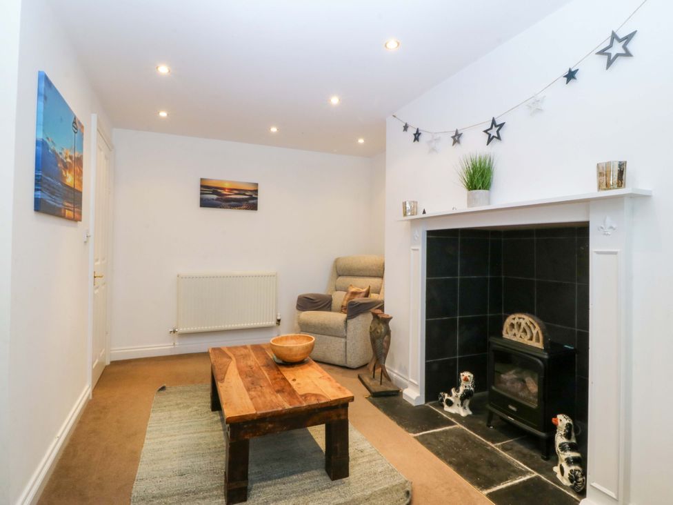 A living room with a sofa, coffee table, and fireplace at Jack's House in Tywyn